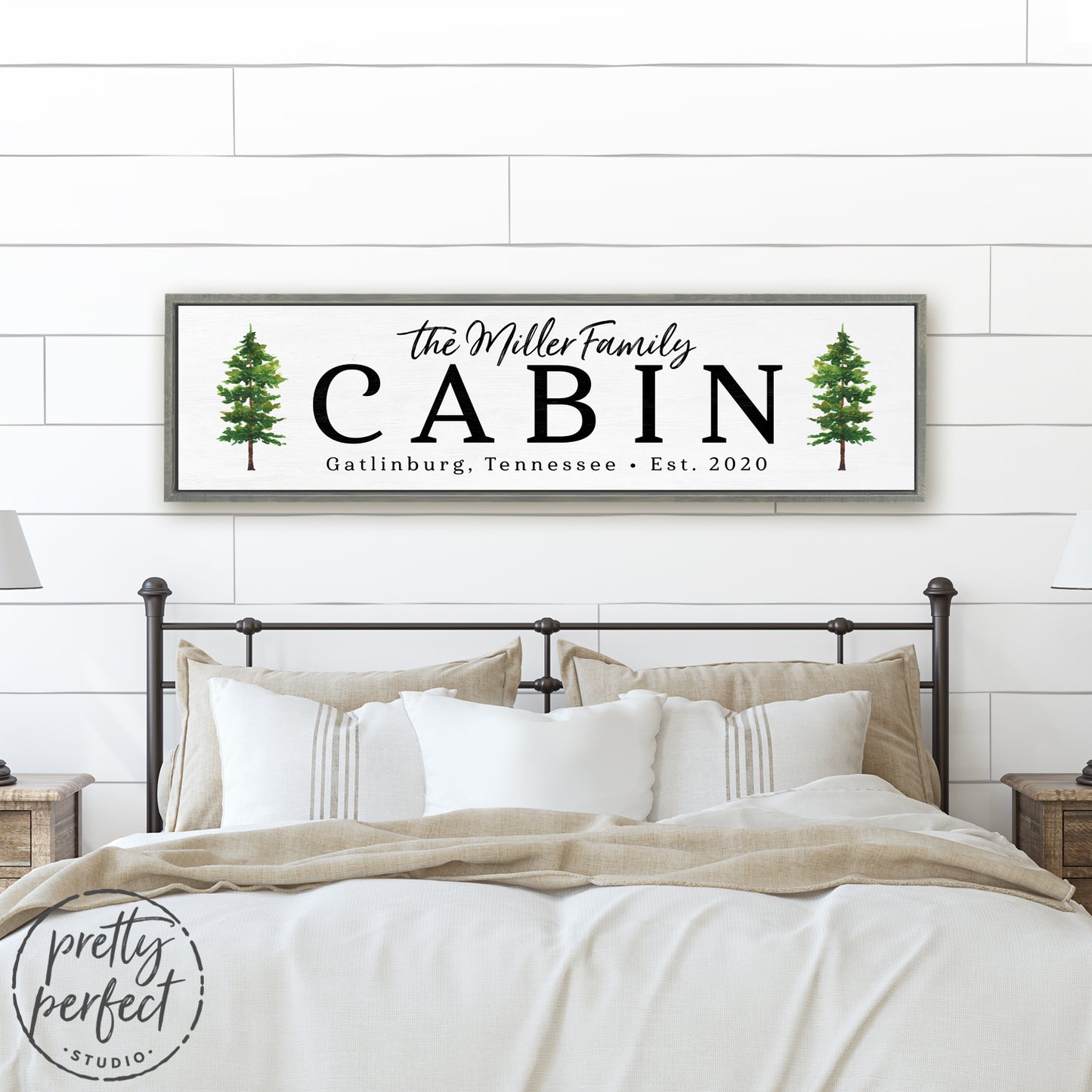 personalized cabin sign with family name and pine tree design, custom rustic cabin wall art above cozy neutral bedroom bed