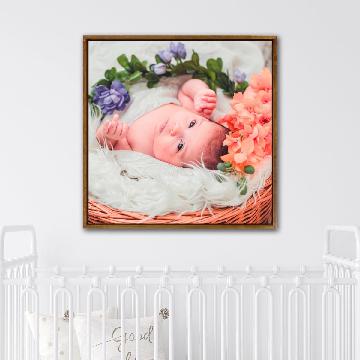 Custom newborn photo canvas print in wood square frame displayed above crib as nursery wall art