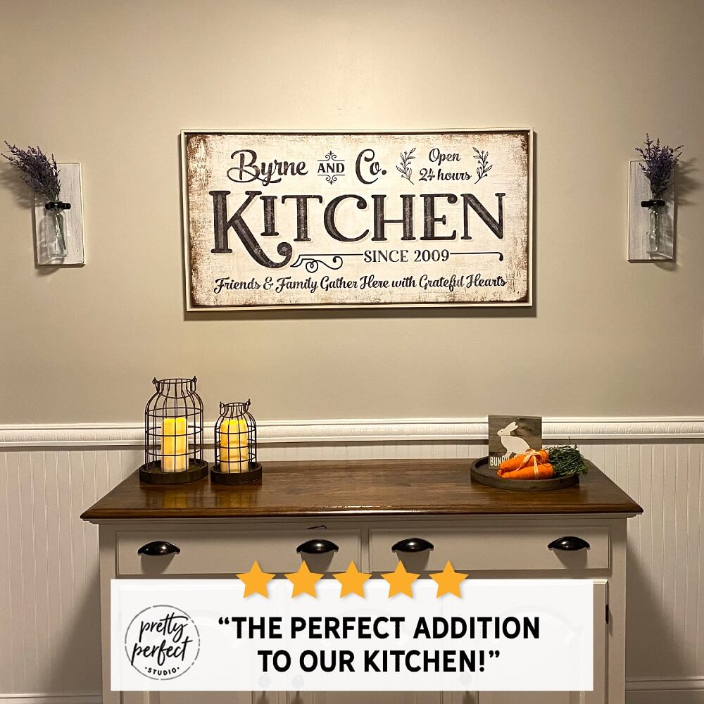Personalized farmhouse kitchen wall sign reading “Byrne and Co. Kitchen” above a wooden buffet table with candles and decor, adding a warm rustic touch to a dining space