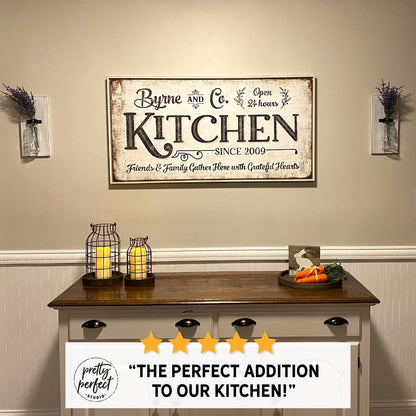 Personalized farmhouse kitchen wall sign reading “Byrne and Co. Kitchen” above a wooden buffet table with candles and decor, adding a warm rustic touch to a dining space