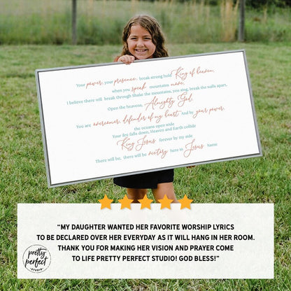 Child holding a framed print of worship lyrics in a grassy outdoor setting