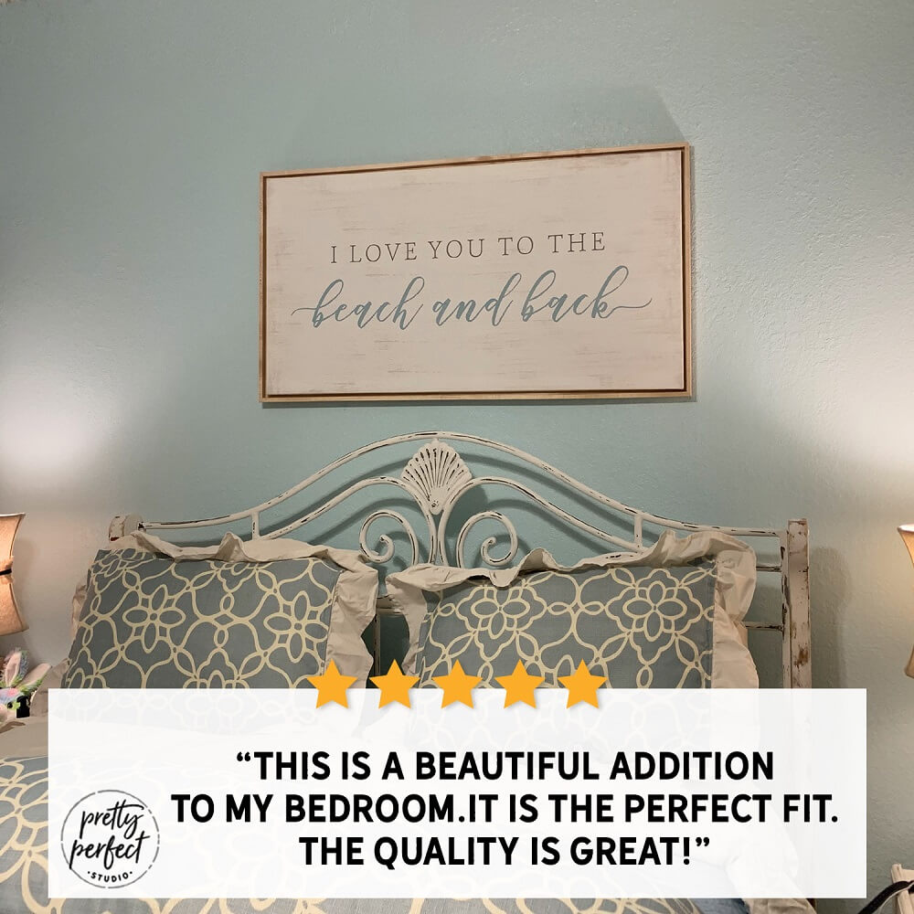 Framed “I love you to the beach and back” wall art above a bed with blue coastal decor pillows, adding a soft beach-themed touch to a bedroom