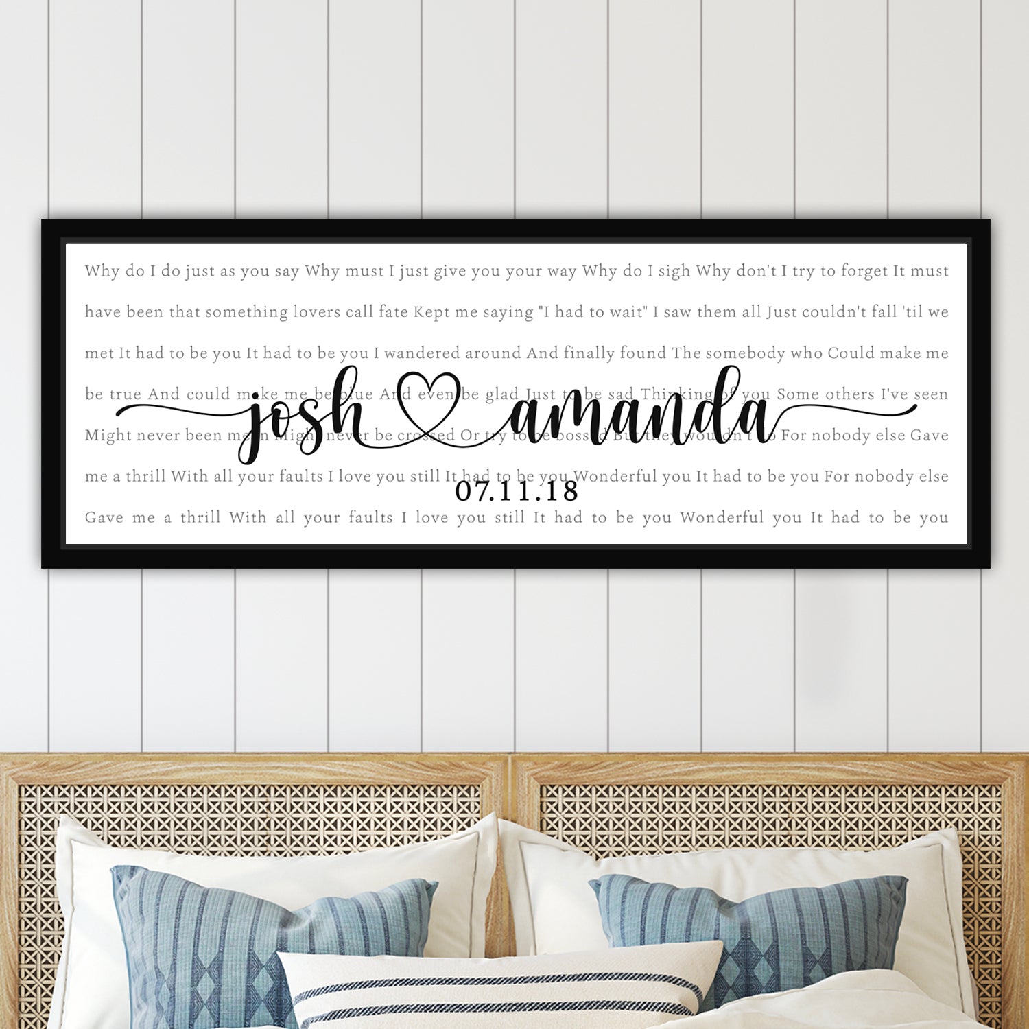 Framed personalized song lyrics artwork with song lyrics text and names on a wall above a bed.
