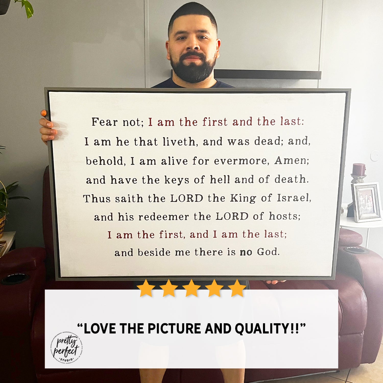 Person holding a framed text with Christian bible verse in a living room setting