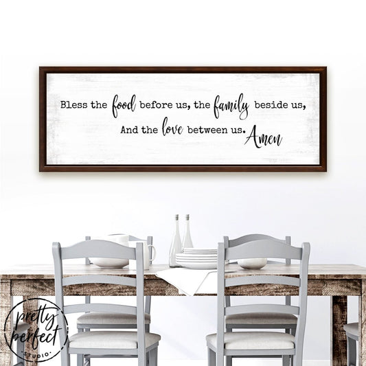 bless the food before us farmhouse kitchen canvas wall art with walnut frame and distressed background above dining table with neutral chairs and table setting