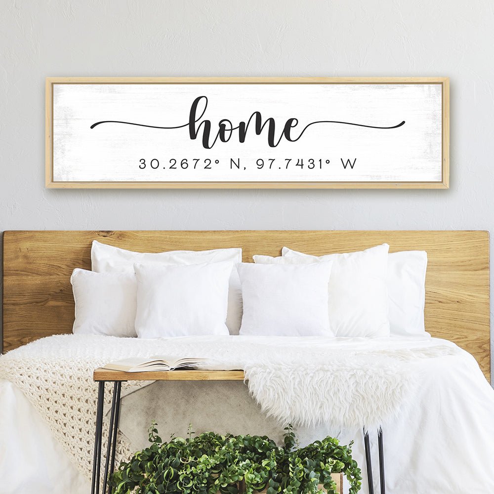 personalized home coordinates sign with distressed white background above modern bedroom bed with neutral decor