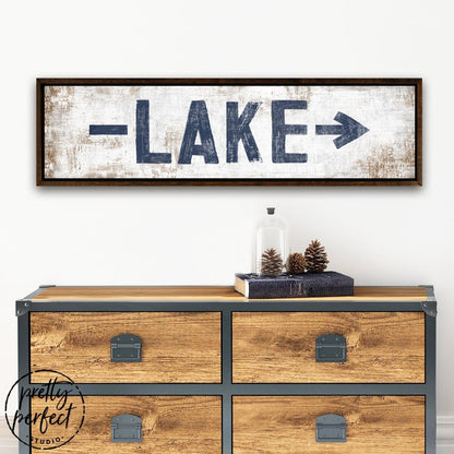 Horizontal lake sign displayed above a wooden console table in an entryway