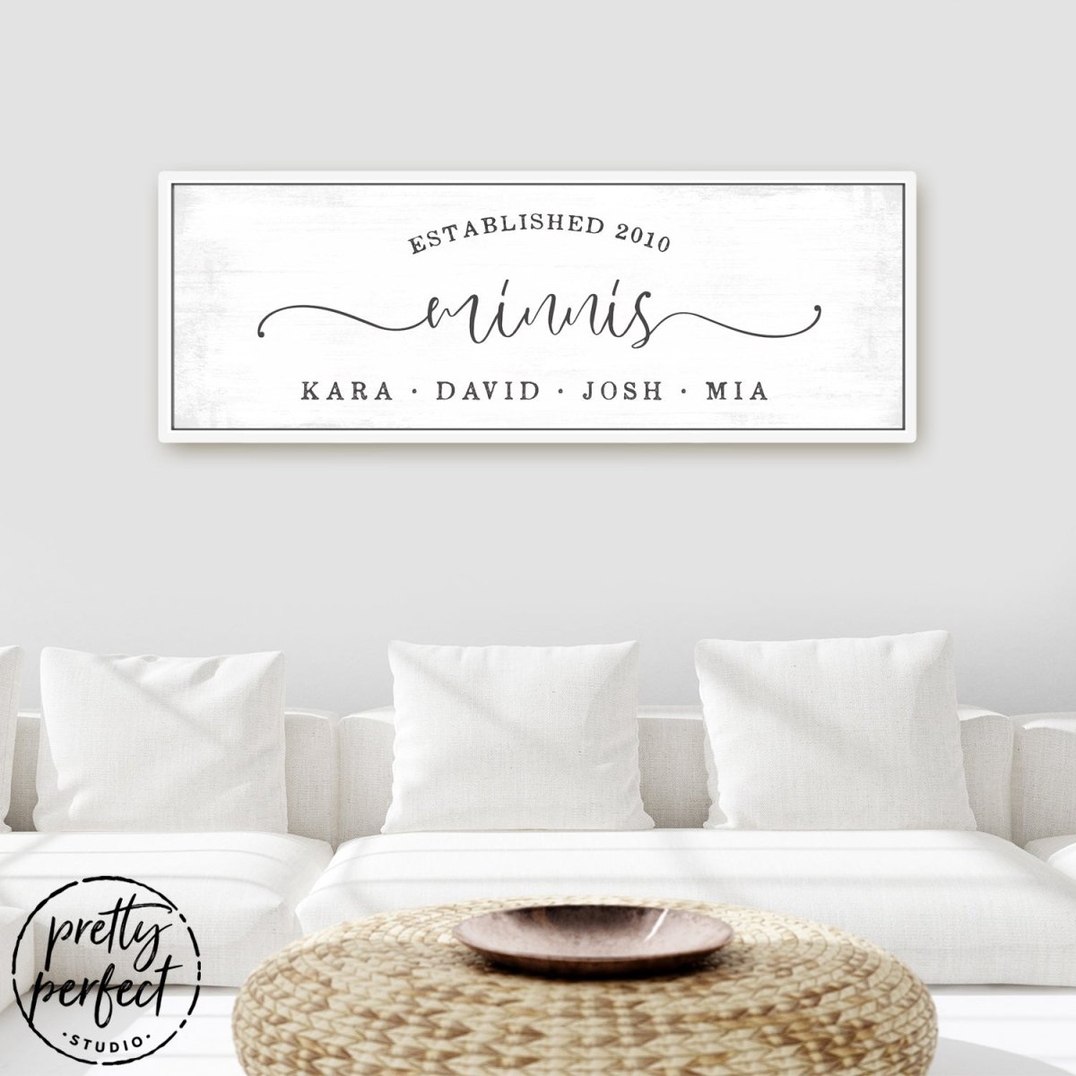 custom last name sign with family members names and established date in modern rustic typography on light distressed background above white sofa